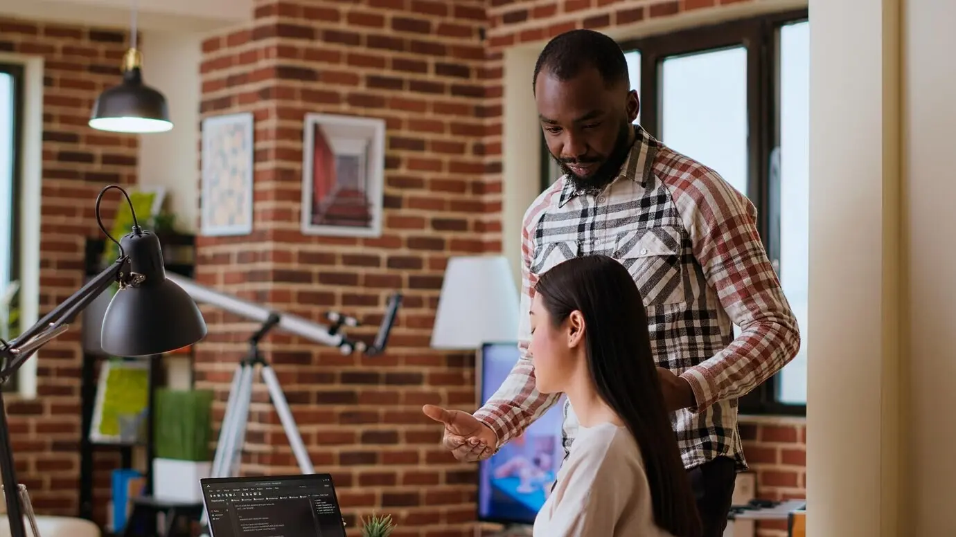 Разнообразная команда разработчиков программного обеспечения пишет код на ноутбуке в уютном домашнем офисе.